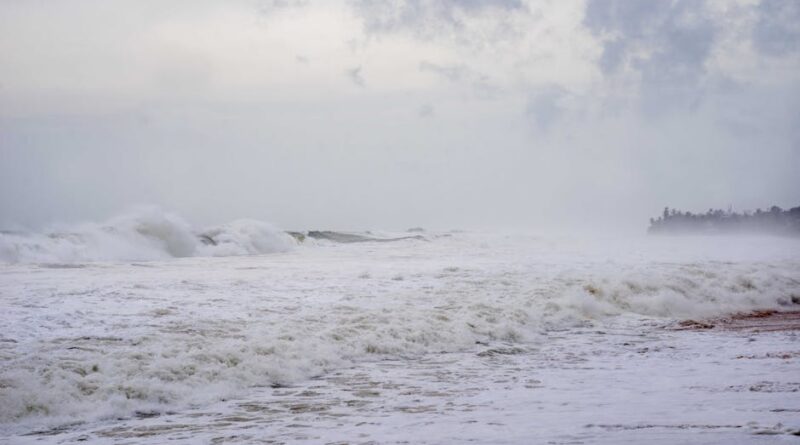 A stormy beach scene with crashing waves and mist, creating a moody atmosphere.