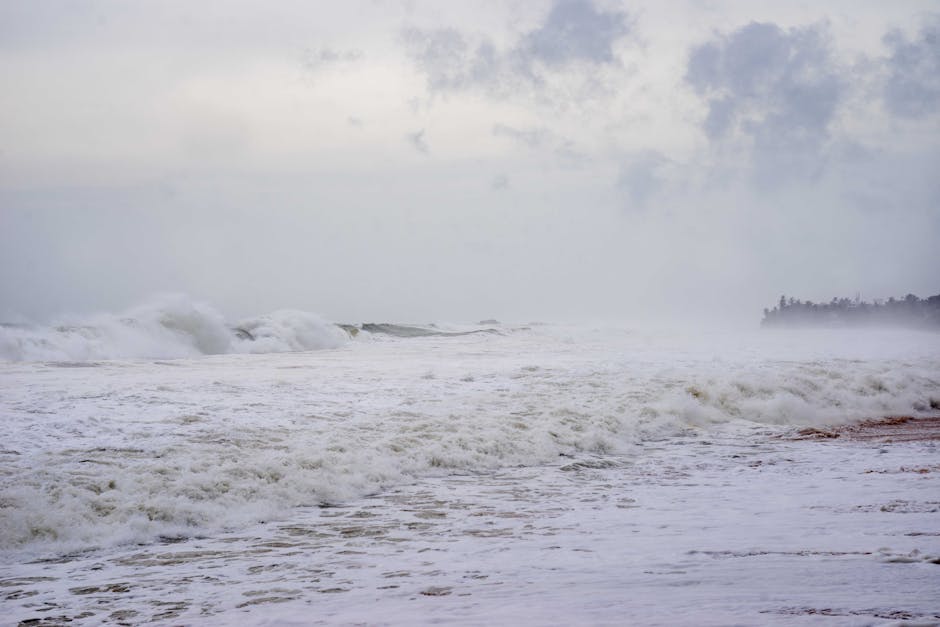 A stormy beach scene with crashing waves and mist, creating a moody atmosphere.
