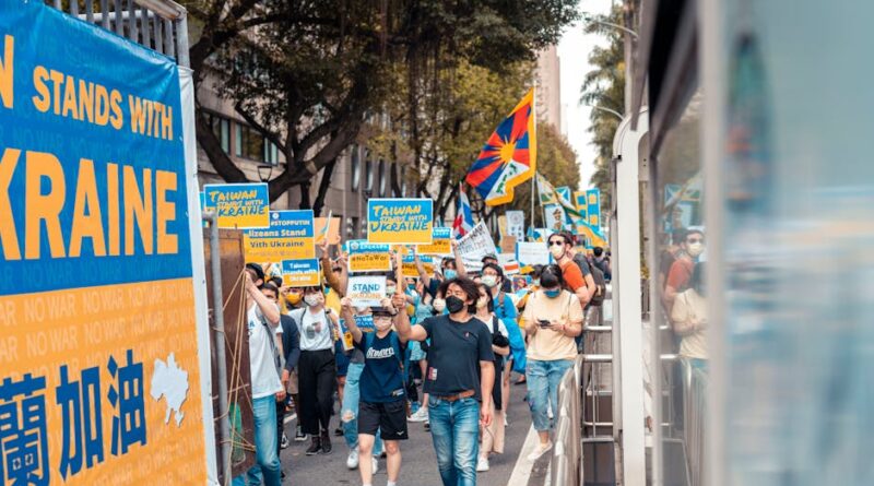 A vibrant protest supporting Ukraine with large crowd, banners, and colorful flags outdoors.