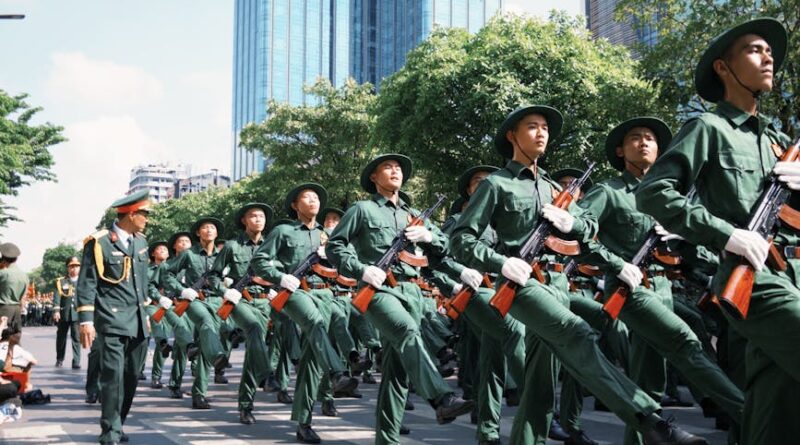 Marching soldiers in green uniforms participate in a city military parade.