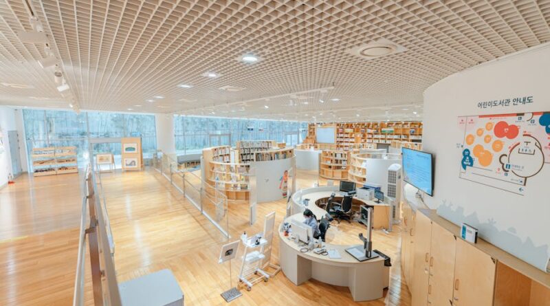 Open and airy modern library with bookshelves, desks, and a large screen in a well-lit space.