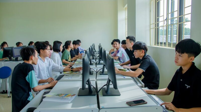 Diverse group of students studying in a computer-equipped classroom setting.