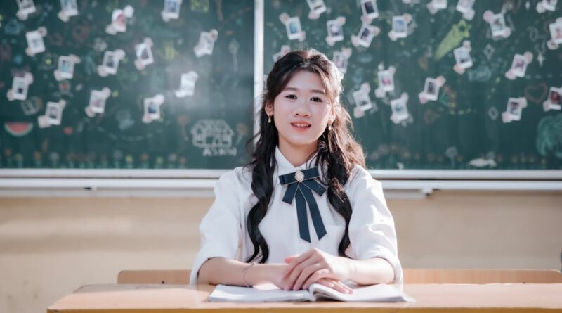 A smiling young student sitting at a desk with a creatively decorated chalkboard in the background.