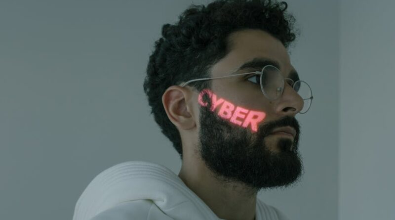 Bearded man with cyber text projection, wearing eyeglasses and white hoodie.