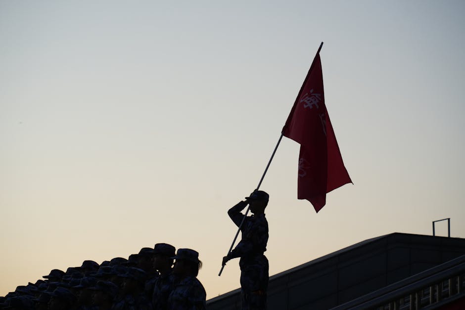 A soldier salutes with a flag during a parade at sunset, creating a striking silhouette.