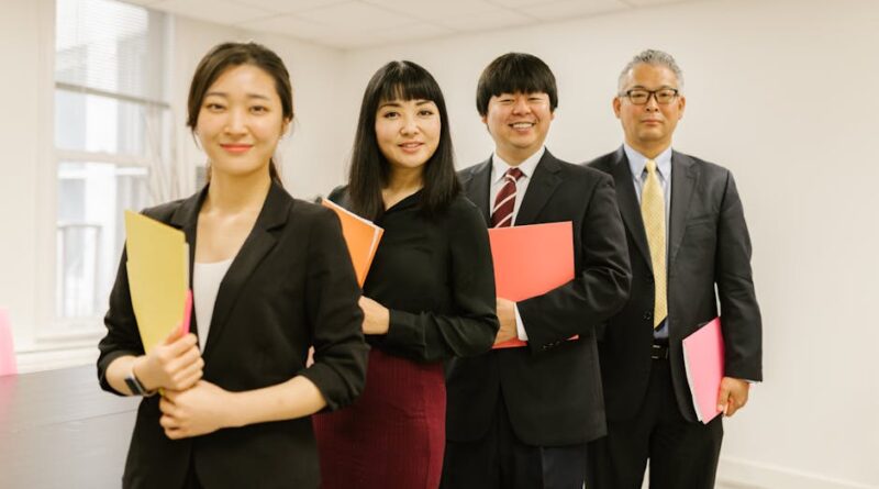 A diverse group of professionals posing confidently in a modern office setting with folders.