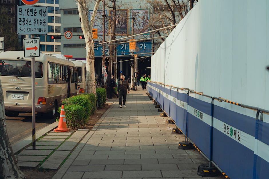 A street in Seoul, South Korea showing buses, pedestrians, and a construction site.