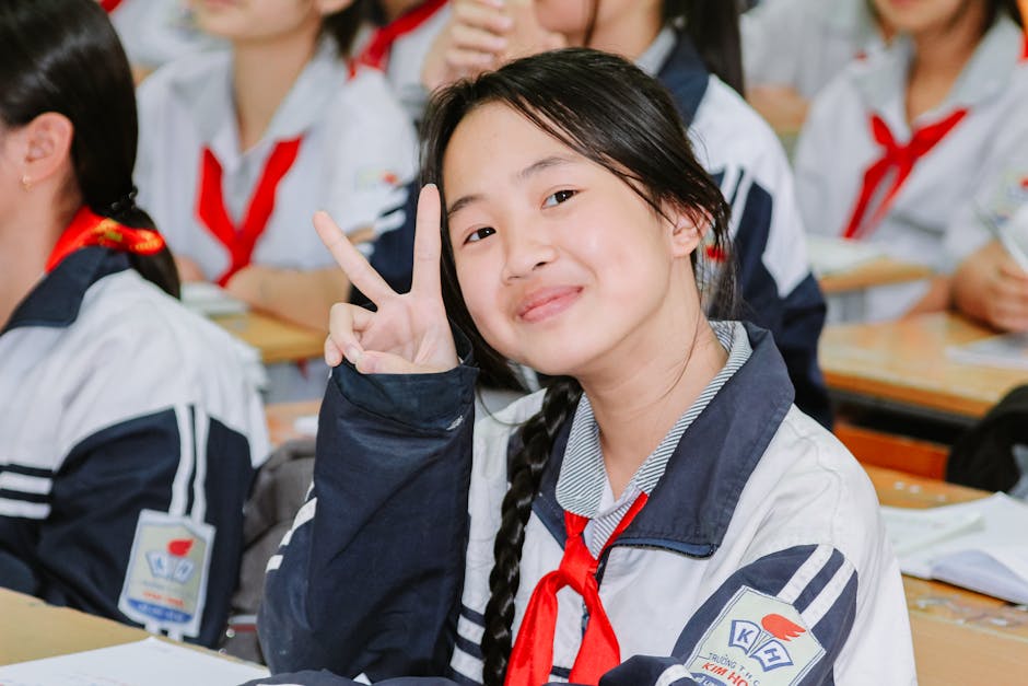 Happy student making peace sign in a classroom setting.