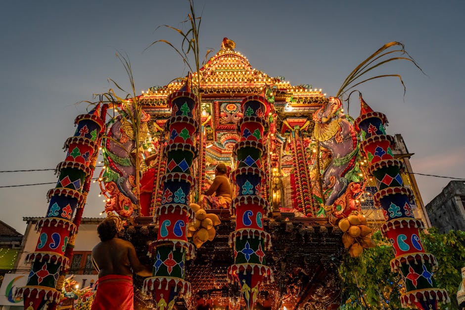Beautifully illuminated festival chariot with intricate designs during a Hindu celebration at twilight.