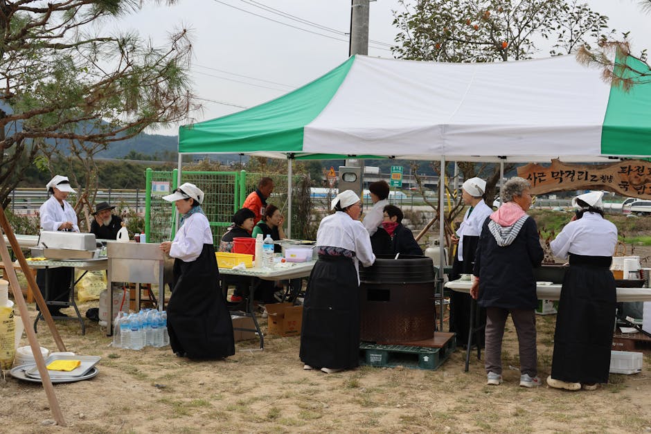 Korean outdoor market stall with people in traditional attire preparing food.