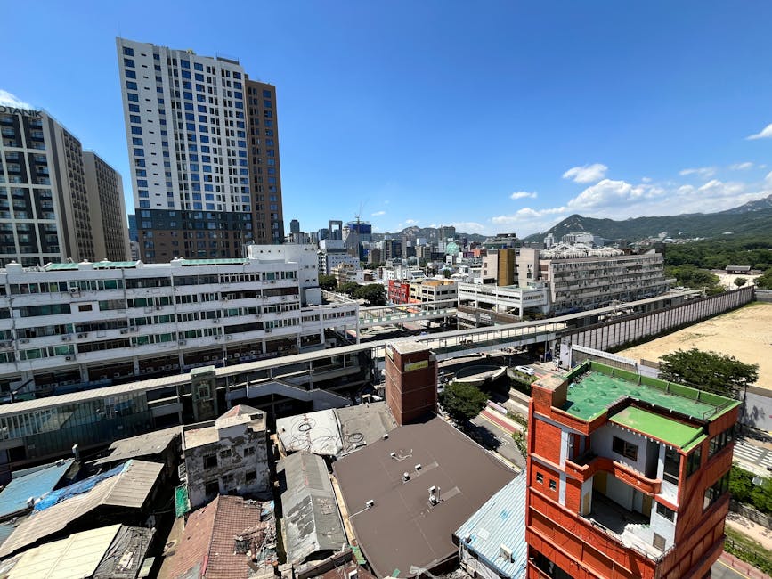 Aerial view of a bustling cityscape with skyscrapers under a clear blue sky.