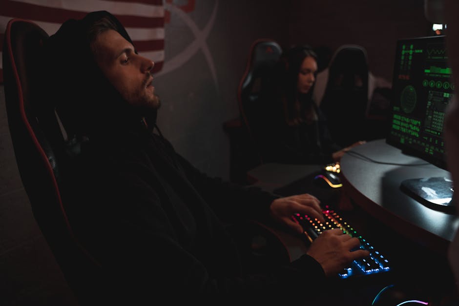 Young adults working on cybersecurity tasks in a dimly lit tech environment.