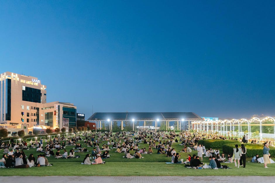 A vibrant evening event in an illuminated urban park in Gwangju, South Korea, with people enjoying leisure activities.