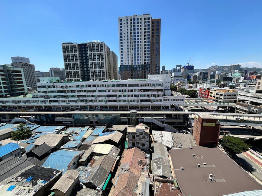 Aerial view of city skyline blending modern skyscrapers and older architecture under a clear blue sky.
