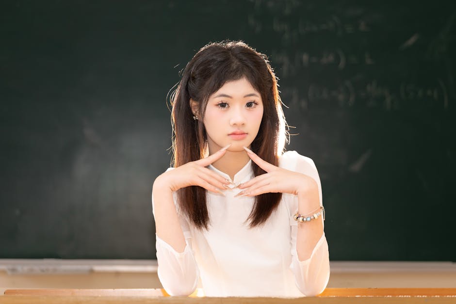 Portrait of a young woman sitting in a classroom with a blackboard background in Hanoi, Vietnam.