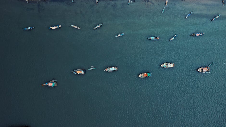 Drone shot of scattered boats floating on a tranquil blue sea.