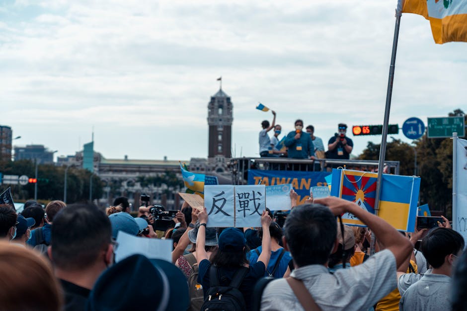 Crowd protests with various flags and signs in front of prominent building.