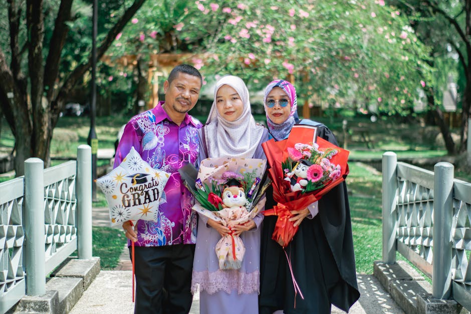 A family celebrates graduation outdoors in Shah Alam, Malaysia, showcasing cultural attire and joy.