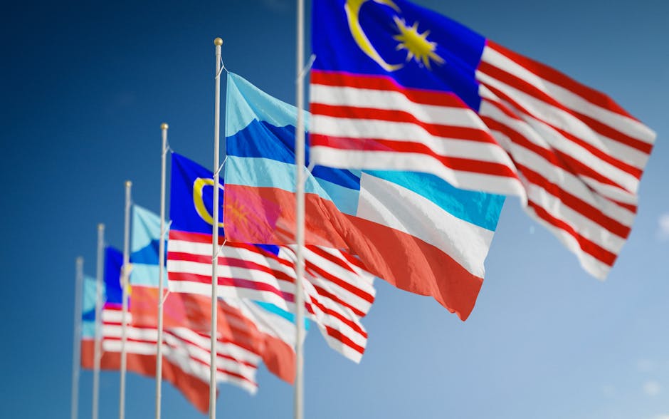 Waving Malaysian and Sabah flags against a clear blue sky, showcasing national pride