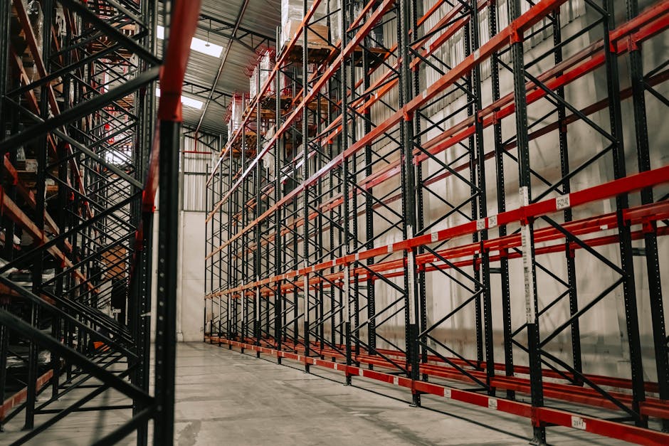 Spacious warehouse interior featuring empty metal racks and high ceiling.