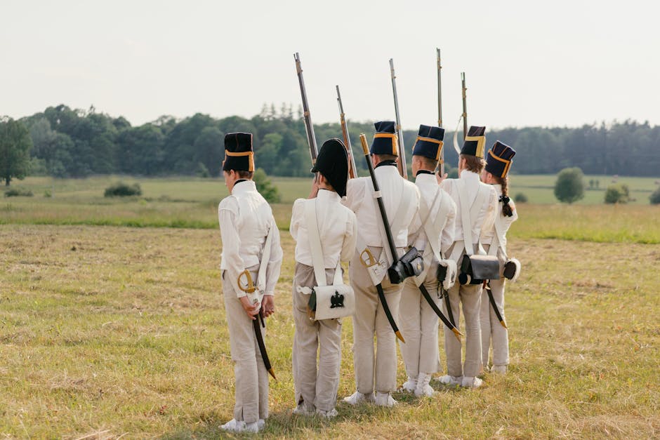 Group of reenactors in historical military uniforms standing in formation outdoors.