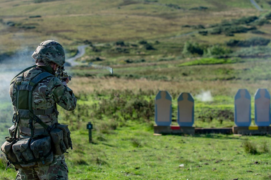 A soldier in military gear engages in shooting practice on an outdoor range.