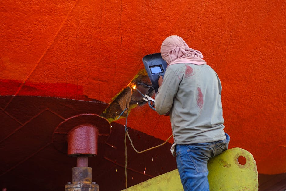 A worker welds the hull of a ship in Dhaka, illustrating industrial labor in shipyards.