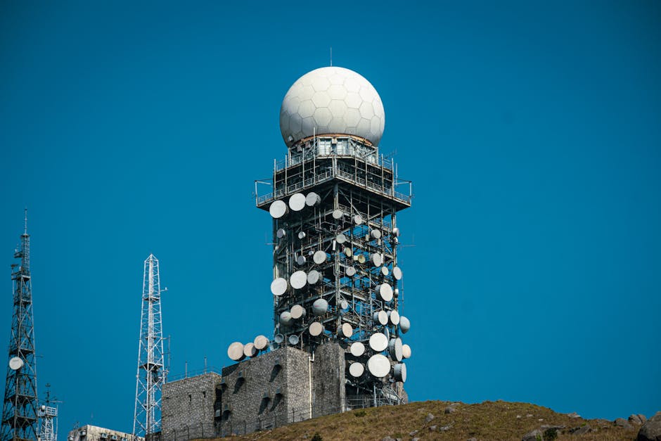 Imposing satellite tower with numerous dishes against a vibrant blue sky.