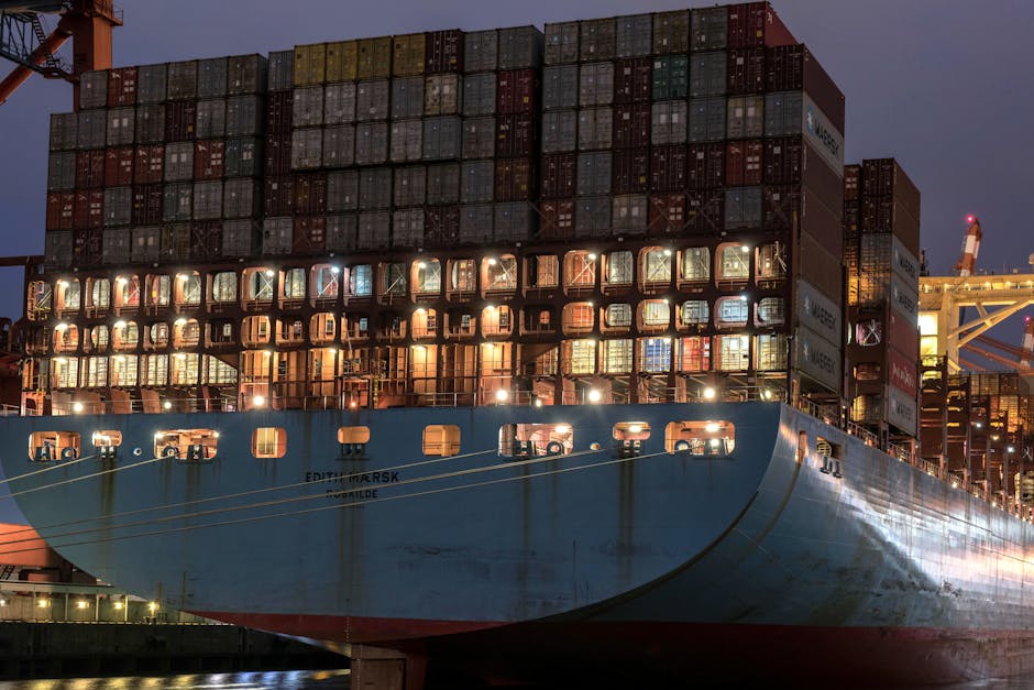 Large container ship Edith Maersk docked at Hamburg harbor during evening lights.